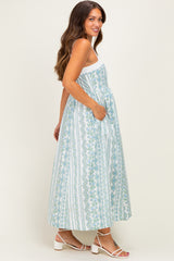 woman wearing a floral print maternity maxi dress with adjustable straps and pockets, showing her baby bump