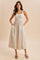 woman wearing a cream maxi dress with floral patterns and square neckline, standing with hands on hips