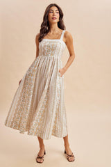 woman wearing a white floral midi dress with adjustable straps and side pockets