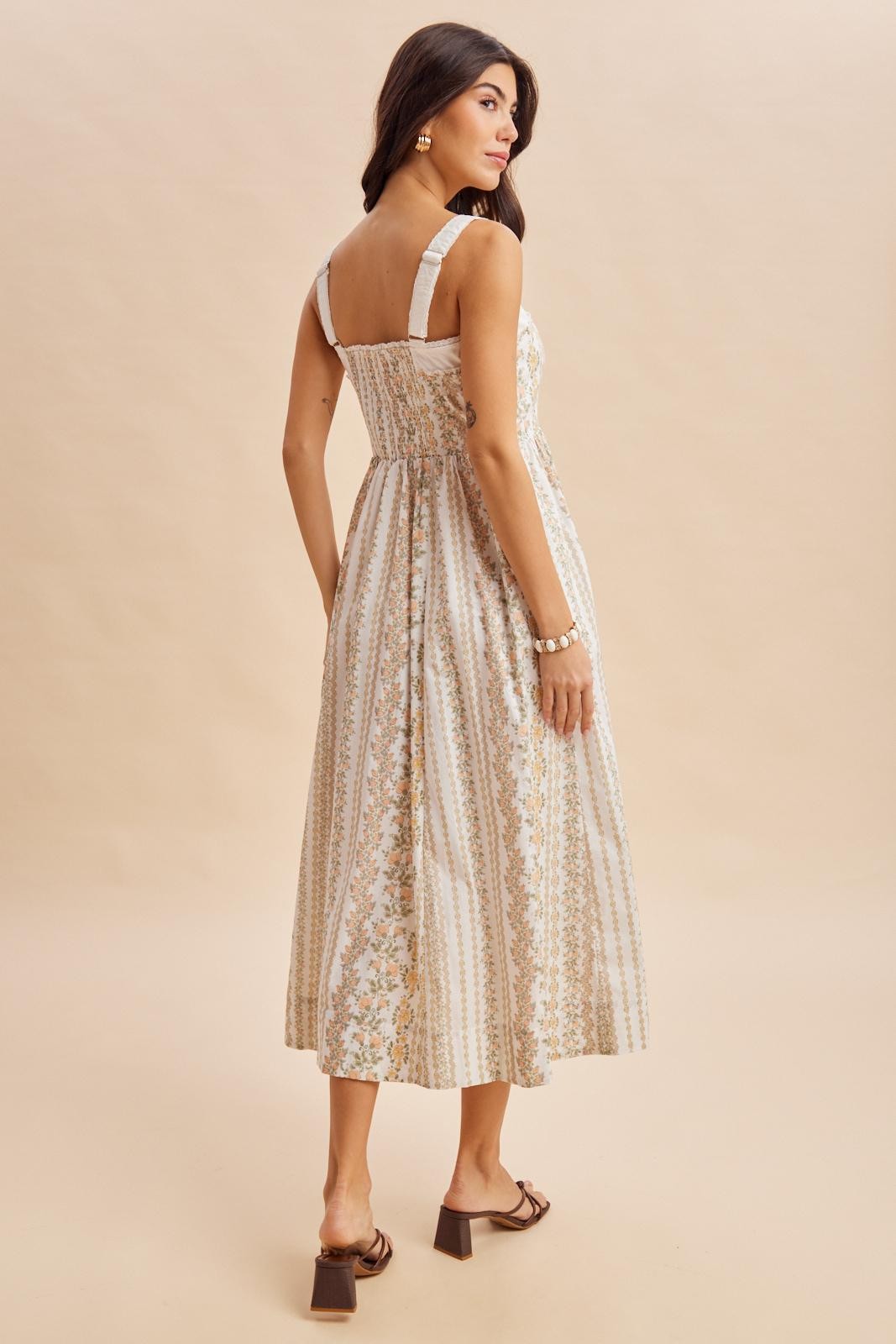 woman wearing a back view of a light beige floral maxi dress with adjustable straps and a fitted bodice