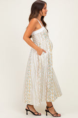 woman wearing a white floral print maternity maxi dress with pockets and showing her baby bump