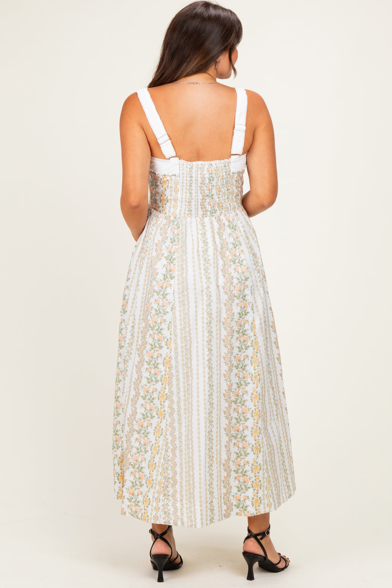 woman wearing a white floral maternity maxi dress with adjustable straps and a smocked back design
