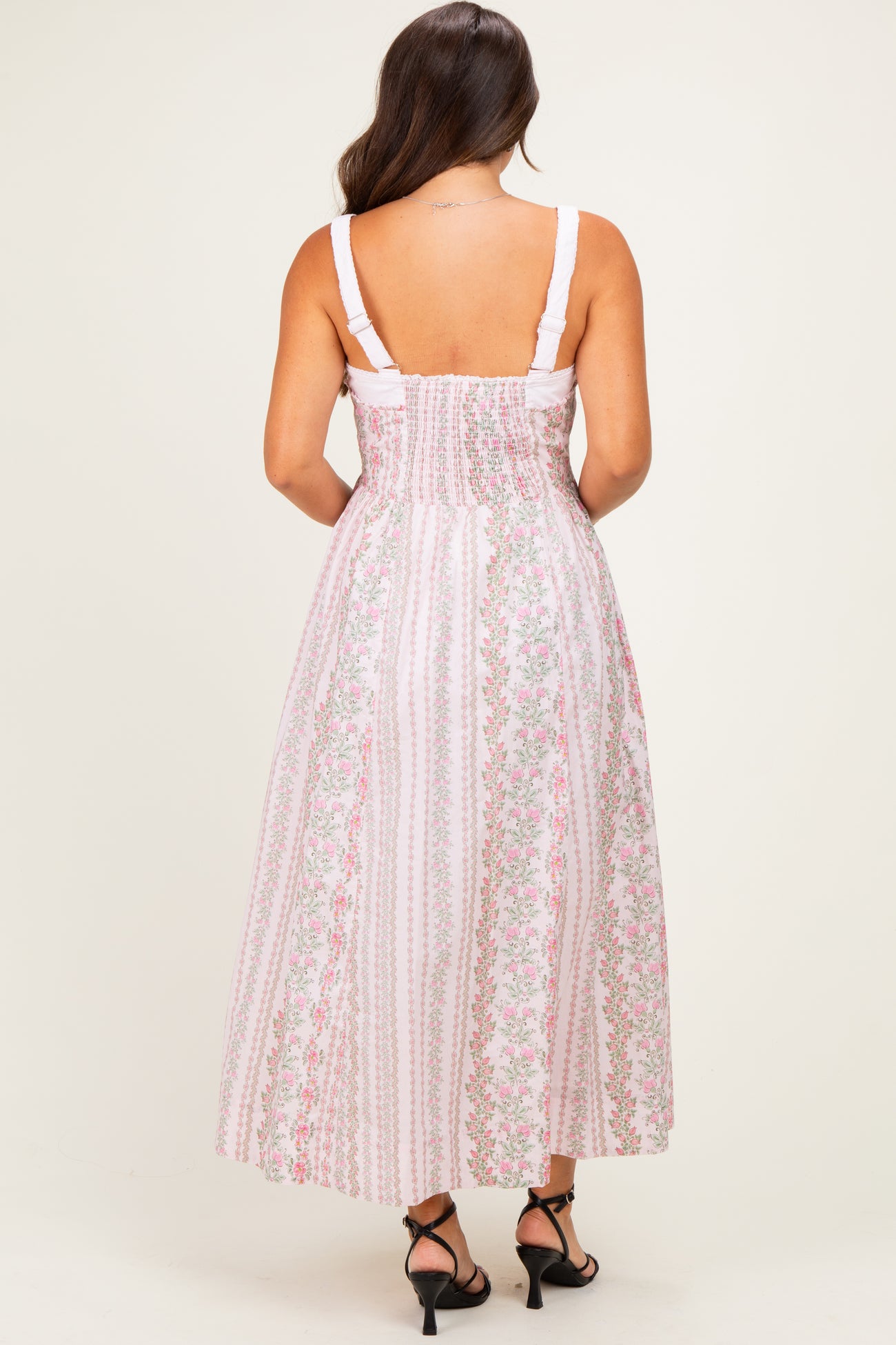 woman wearing a pink floral maternity maxi dress with a smocked back and adjustable straps