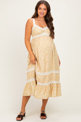 woman wearing a yellow floral maternity dress with lace trim and a baby bump