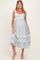 woman wearing a light blue floral maternity dress with lace detailing and a flowing skirt, showcasing her baby bump