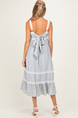 woman wearing a light blue floral maternity dress with lace details and a bow at the back