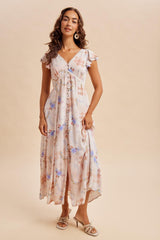 woman wearing a cream floral maxi dress with ruffle sleeves and a cinched waist