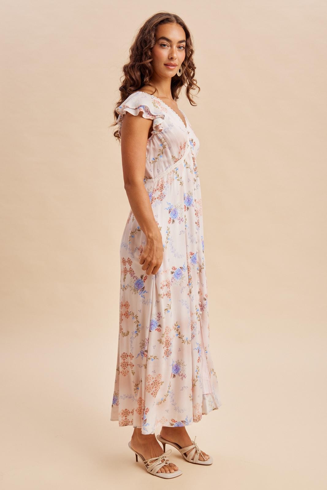 woman wearing a floral print maxi dress with ruffled sleeves and a flowy silhouette