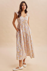 woman wearing a floral maxi dress with ruffled cap sleeves and pockets, standing on a neutral background