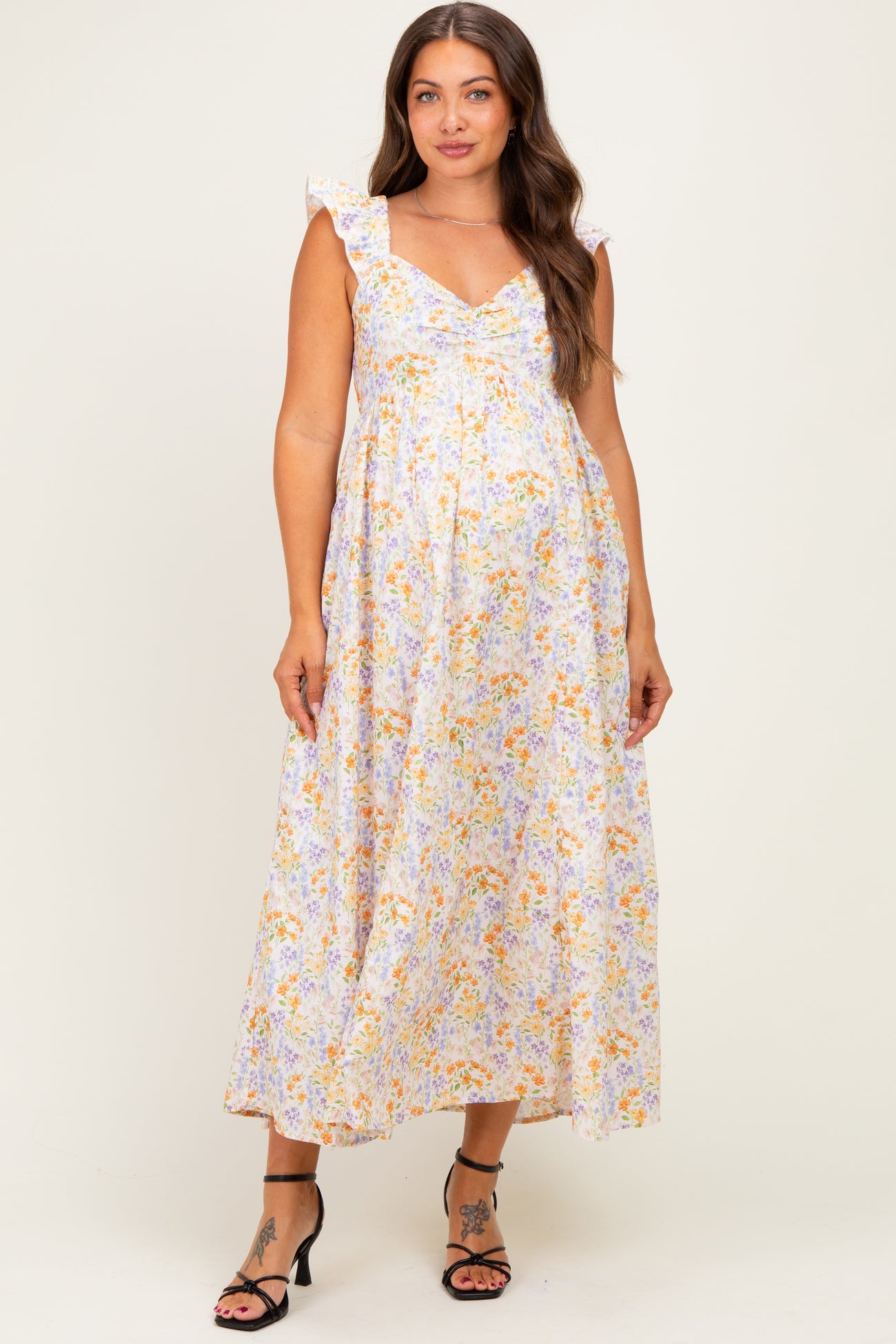 woman wearing a floral print maternity maxi dress with ruffled straps and a flowing silhouette