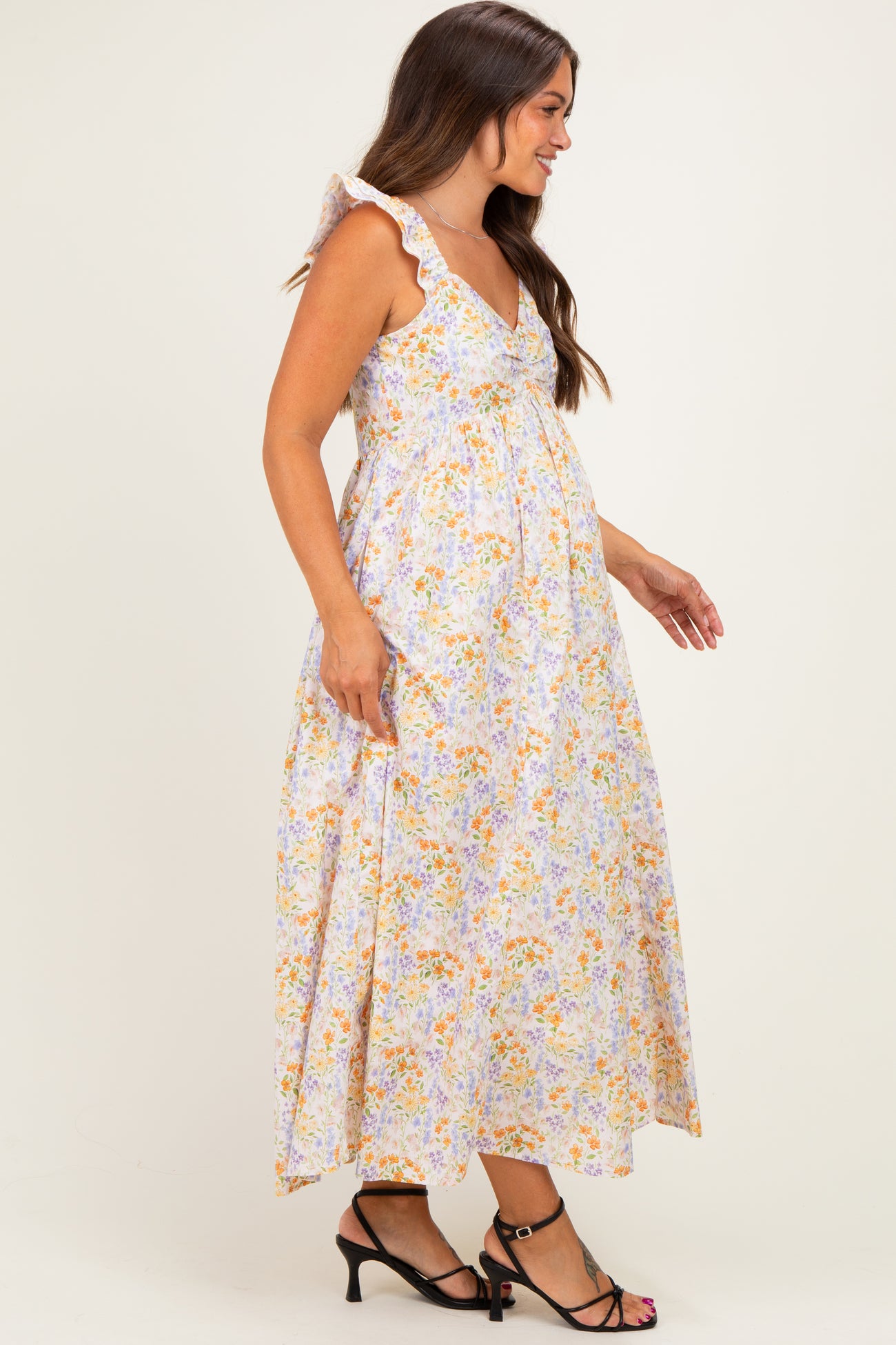 woman wearing a floral maternity maxi dress with ruffle straps and a visible baby bump