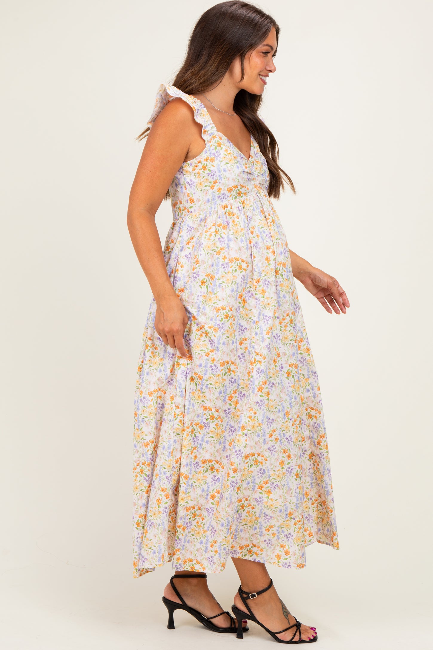 woman wearing a floral maternity maxi dress with ruffle straps and a visible baby bump