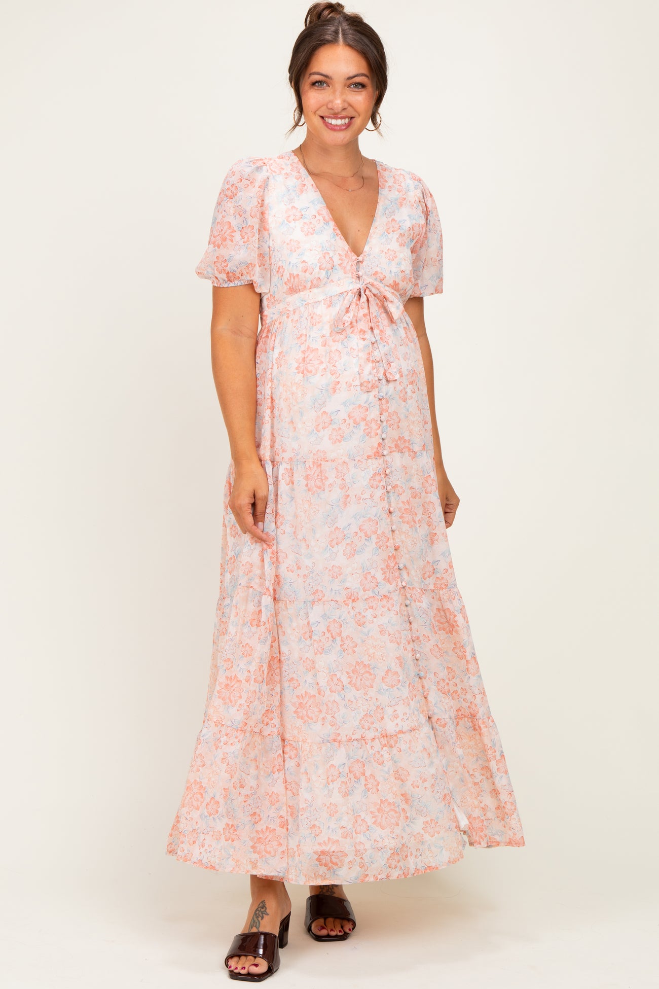 woman wearing a floral maternity maxi dress with short sleeves and a tie detail at the bust, showing her baby bump