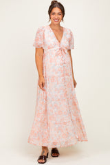 woman wearing a floral maternity maxi dress with short sleeves and a tie detail at the bust, showing her baby bump