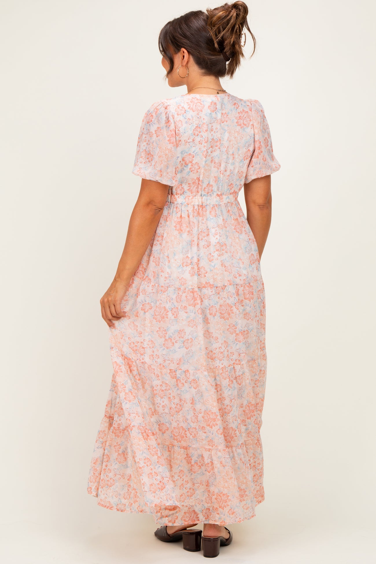 woman wearing a light pink floral maternity maxi dress with short sleeves and an elastic waistband