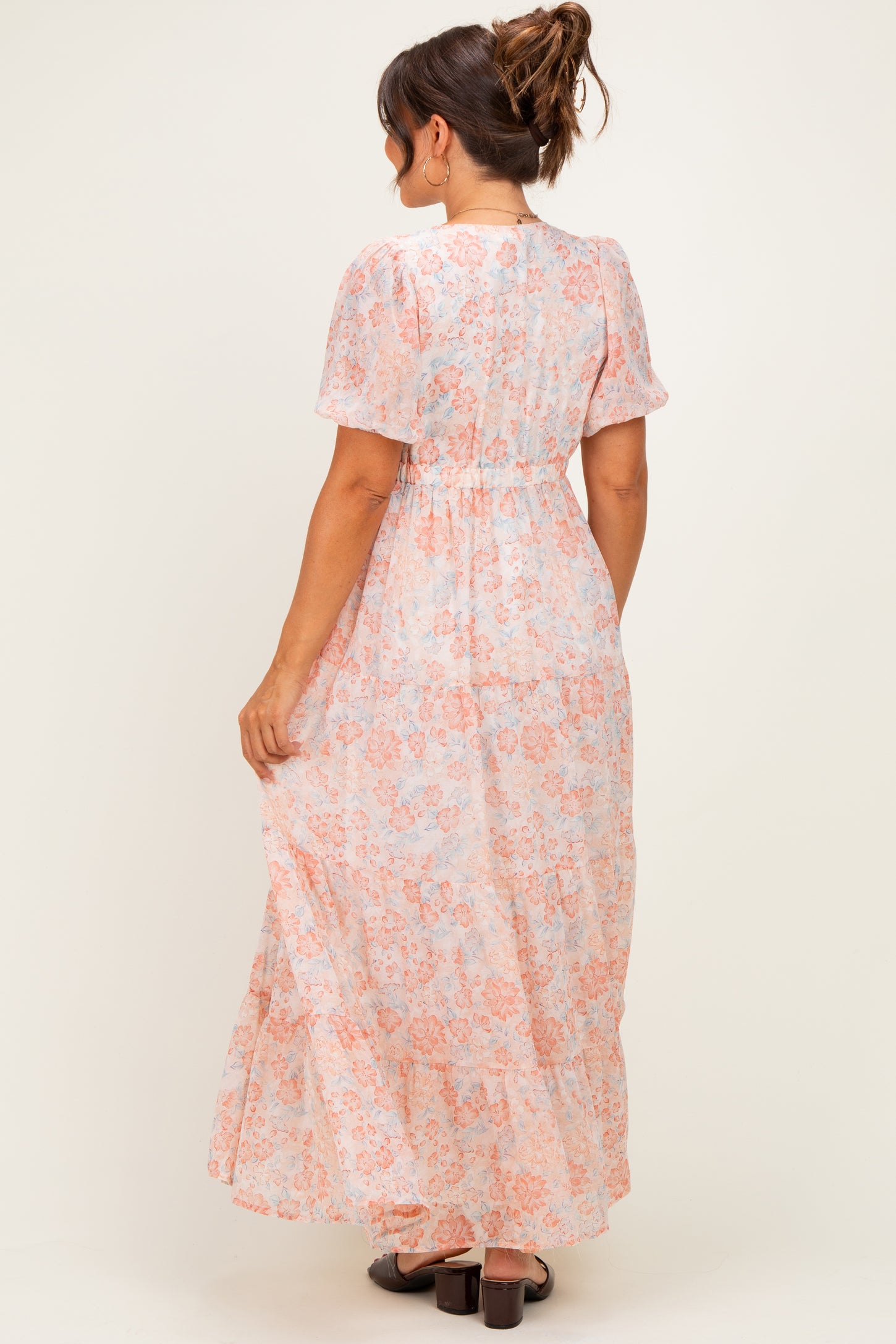 woman wearing a light pink floral maternity maxi dress with short sleeves and an elastic waistband