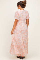 woman wearing a light pink floral maternity maxi dress with short sleeves and an elastic waistband