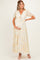 woman wearing a yellow floral maternity maxi dress with a tie front and puff sleeves, showing her baby bump