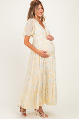 woman wearing a floral yellow maternity maxi dress and holding her baby bump