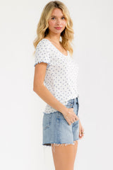 woman wearing a white short sleeve v-neck top with blue floral print and denim cut-off shorts