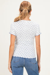 woman wearing a short sleeve white maternity top with blue floral patterns and scalloped edges, showing her back