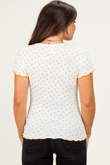 woman wearing a white maternity top with yellow floral print and orange scalloped sleeves, showing her back