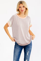 woman wearing a striped short sleeve top with pastel color blocking and distressed blue jeans