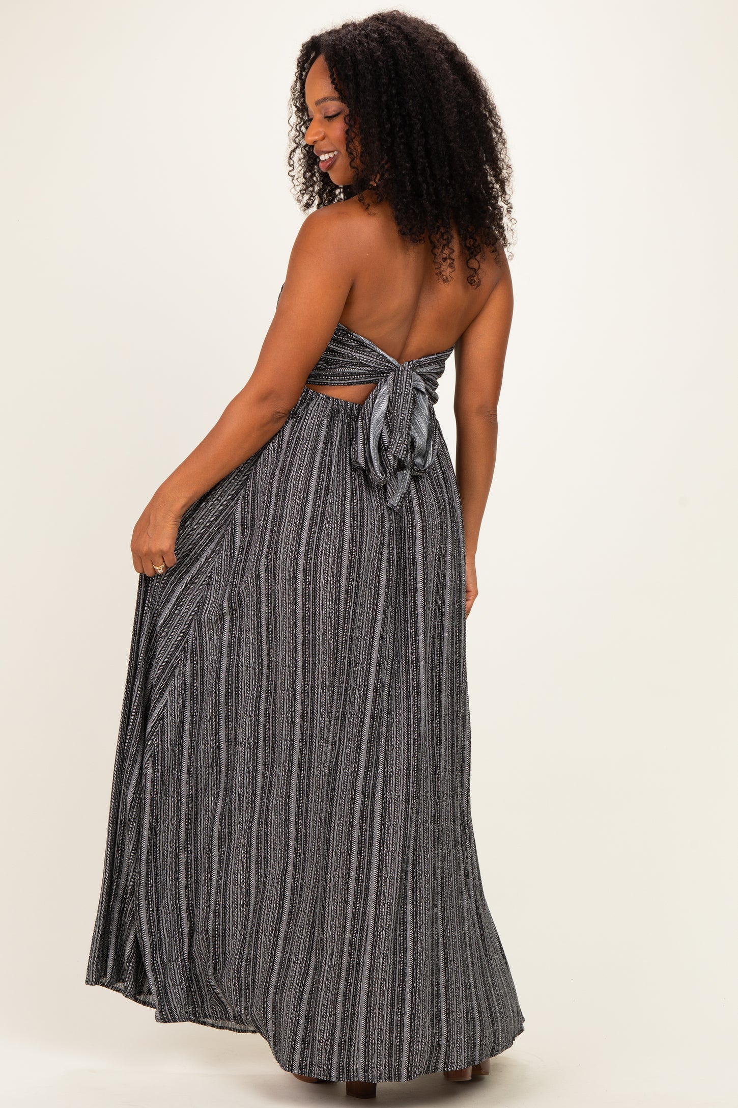woman wearing a black and white striped strapless maxi dress with a tied back detail