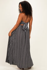 woman wearing a black and white striped strapless maxi dress with a tied back detail