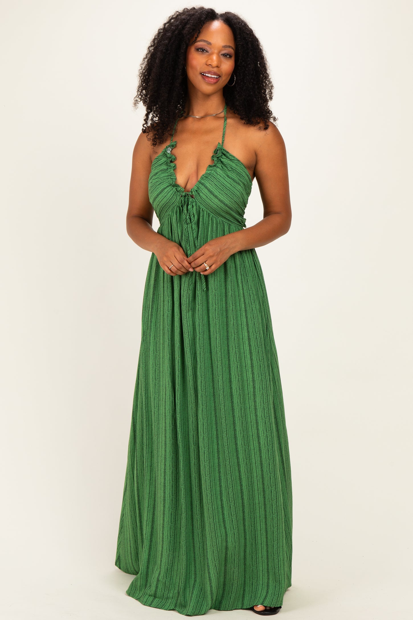 woman wearing a green halter maxi dress with a ruffled neckline and textured fabric
