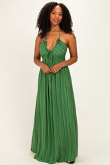 woman wearing a green halter maxi dress with a ruffled neckline and textured fabric