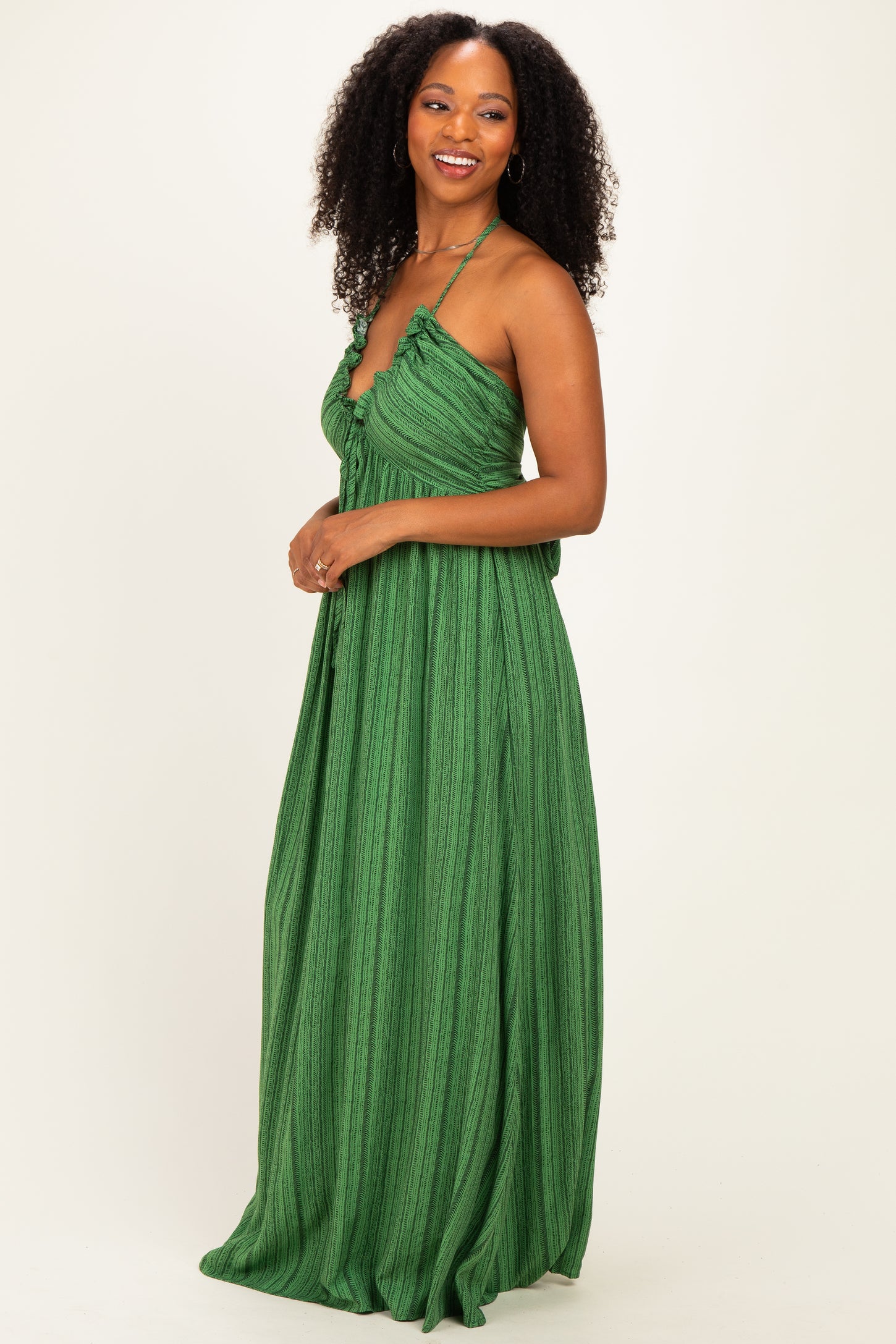 woman wearing a green halter neck maxi dress with pleated detailing and flowy silhouette