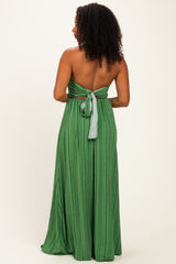 back view of a woman wearing a green striped maxi dress with a tied open back design