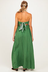 woman wearing a green backless maternity maxi dress with a halter neck and tie detail at the back