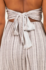 woman wearing a beige backless dress with a tie detail and textured pattern