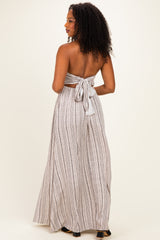 woman wearing a backless striped maxi dress with a tied bow detail at the waist