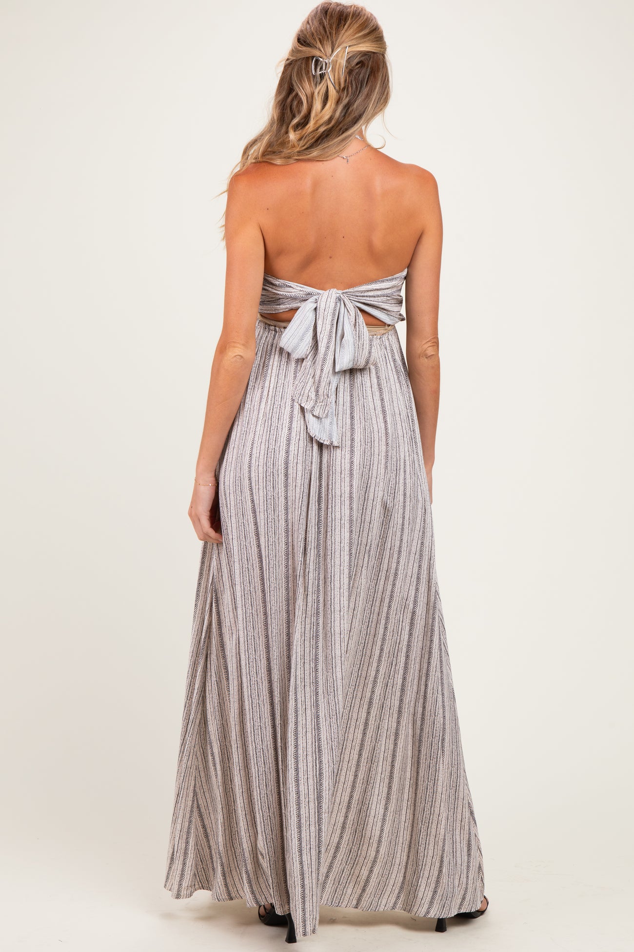 woman wearing a striped backless maternity maxi dress with a bow detail at the back