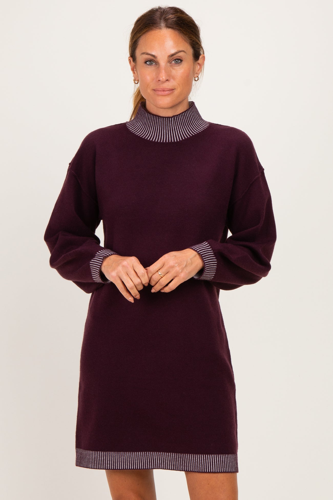 woman wearing a dark purple long sleeve sweater dress with striped collar and cuff details