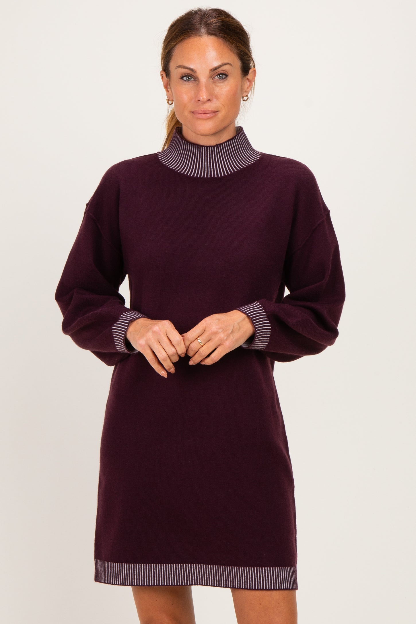 woman wearing a dark purple long sleeve sweater dress with striped collar and cuff details