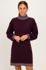 woman wearing a dark purple long sleeve sweater dress with striped collar and cuff details