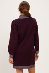 woman wearing a burgundy sweater dress with a striped collar and trim, viewed from the back