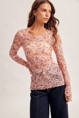 woman wearing a pink floral long sleeve top with a fitted silhouette and scalloped hem, styled with denim jeans