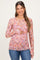 woman wearing a pink floral long sleeve maternity top and holding her baby bump