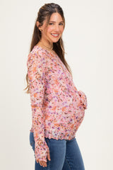 woman wearing a floral long sleeve maternity top with a tie detail and showing her baby bump