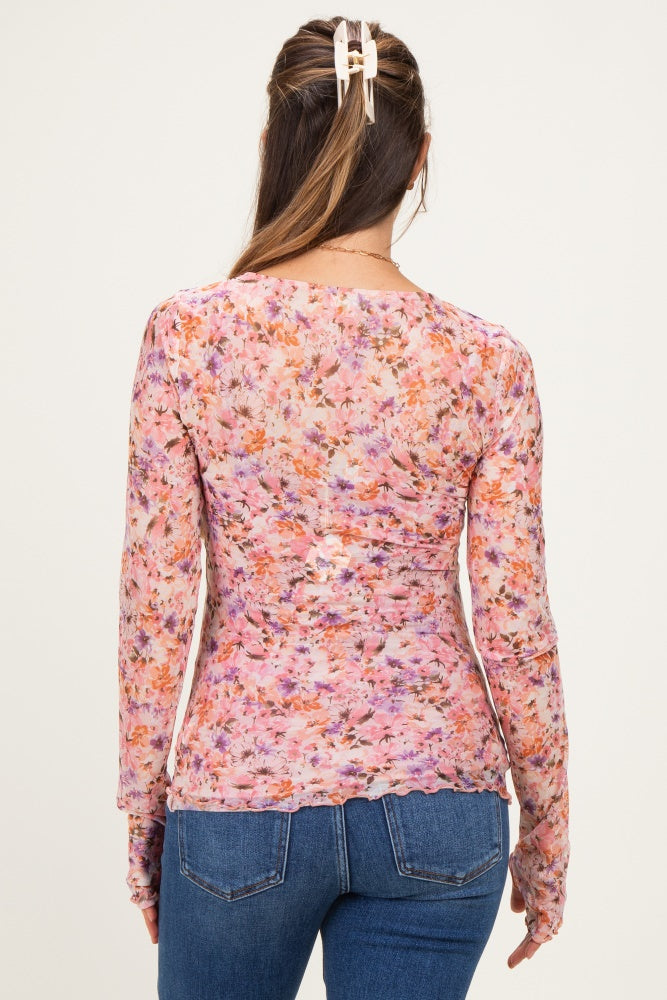 woman wearing a sheer floral maternity top with long sleeves and a fitted silhouette, showing a baby bump