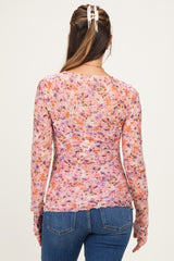 woman wearing a sheer floral maternity top with long sleeves and a fitted silhouette, showing a baby bump