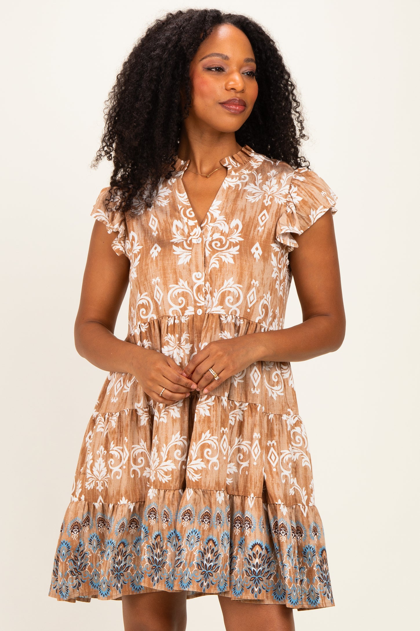 woman wearing a brown and cream patterned short sleeve dress with a tiered skirt and button detail