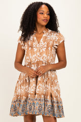 woman wearing a brown and cream patterned short sleeve dress with a tiered skirt and button detail
