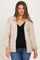 woman wearing a cream oversized maternity cardigan over a black top and blue jeans, showing her baby bump