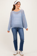 woman wearing a light blue maternity sweater with open knit patterns, paired with blue jeans and white sneakers